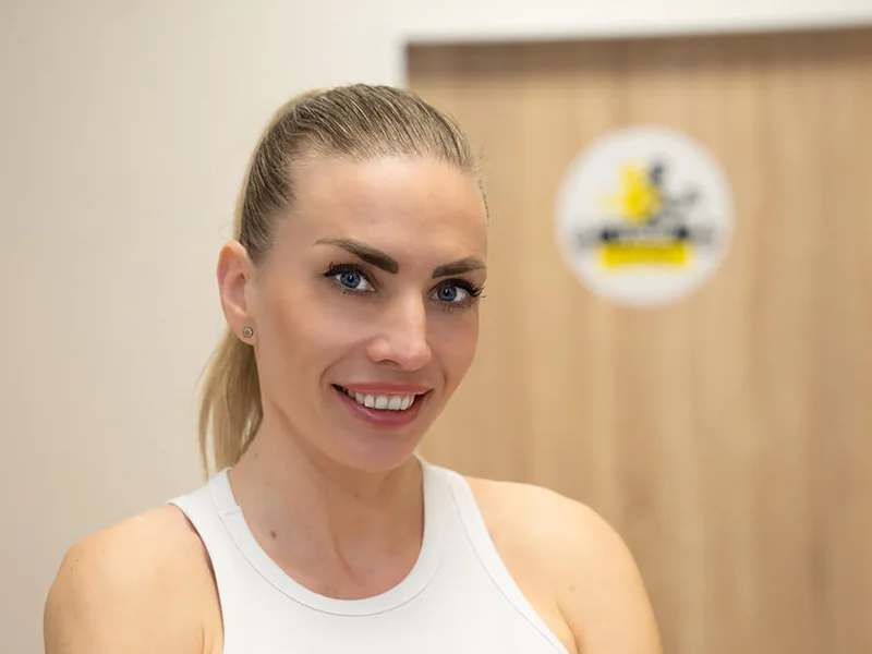 Osobní trenérka Naomi v bílém tílku se založenýma rukama v Tvoje Fitko v Letňanech
